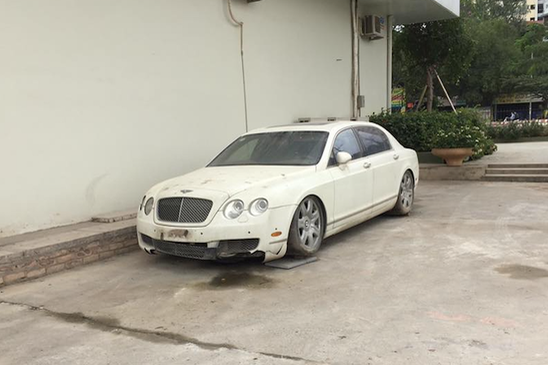 Trong ảnh là chiếc  siêu xe sang Bentley Continental Flying Spur màu trắng bị chủ nhân vứt xó với phần cản trước bị hư hỏng nghiêm trọng, một phần của cản va trước đã biến mất trong khi đèn pha phía bên phải có vẻ bị vỡ cùng với đó là một lớp bám bụi khá dầy.